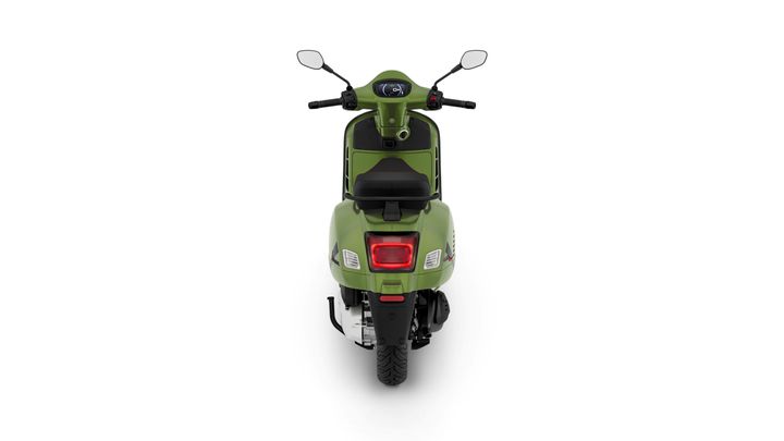 A green scooter is shown from the rear, featuring a sleek design, handlebars, and a digital display on the dashboard. The back has a red taillight and a prominent rear tire. The background is plain white.