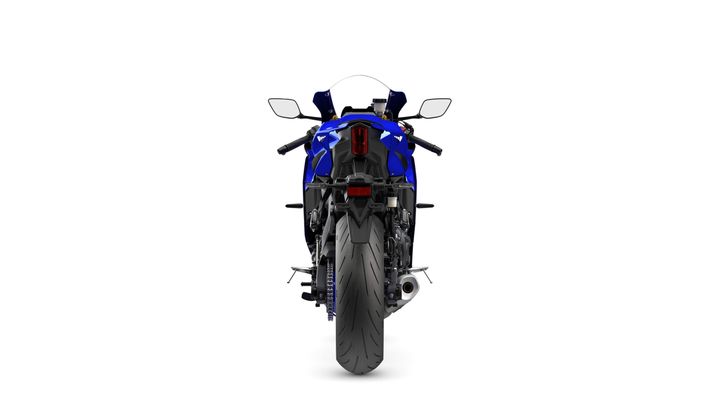 A blue motorcycle viewed from the rear, showcasing its large tire, sleek body, and dual mirrors.