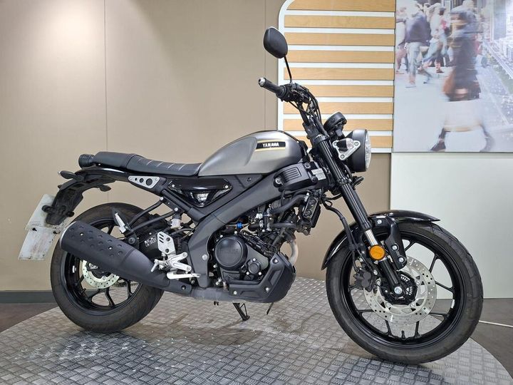 Yamaha XSR 125 2026 A gray Yamaha motorcycle is positioned on a textured floor, showcasing its sleek design and black wheels. The bike features a modern aesthetic with a round headlight and minimalist bodywork, set against a neutral background that suggests an indoor showroom environment.