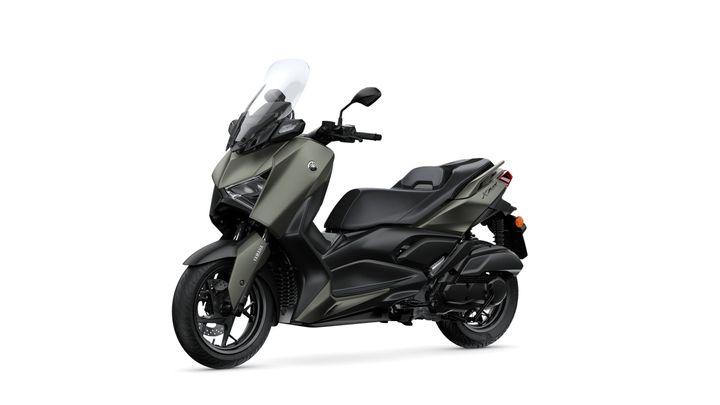 A sleek, modern scooter in matte olive green with a windscreen, featuring a comfortable seat, sporty design, and black accents, positioned at an angle against a white background.