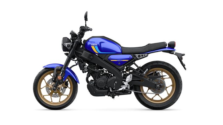 A blue Yamaha motorcycle with gold wheels, featuring a modern design, a black seat, and sporty elements. The bike is positioned on a white background, highlighting its sleek profile and distinctive branding.