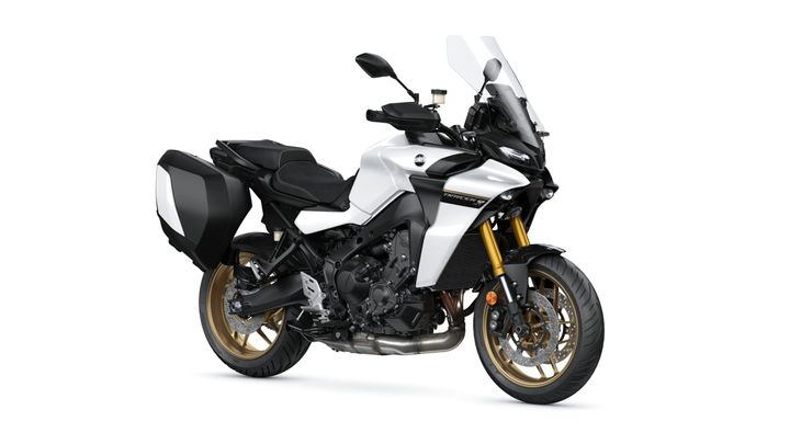 Yamaha 2024 Tracer GT A modern sport-touring motorcycle with a white and black body, featuring a tall windshield, gold forks, and saddle bags on both sides.
