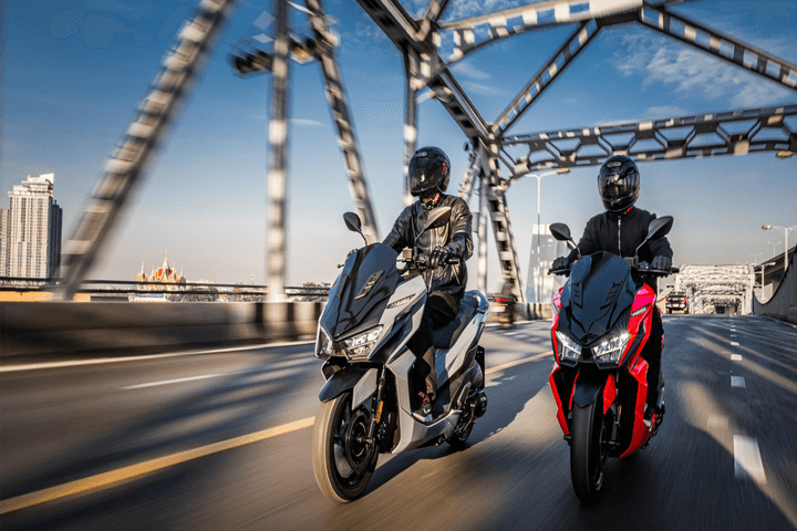 Two SYM Jet X scooter cruising down the road