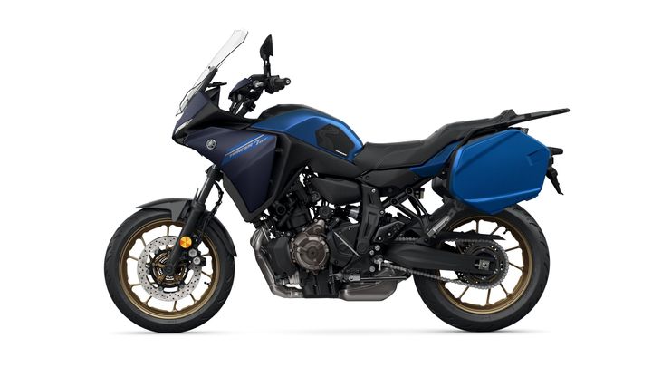 A side view of a blue Yamaha motorcycle with a sleek design, featuring a large windscreen, black seat, and gold-accented wheels. The bike is equipped with a side pannier on the rear.