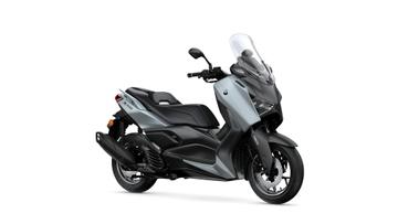 A sleek gray and black Yamaha XMAX scooter, angled to showcase its design, including a windscreen, console, and distinctive body lines.