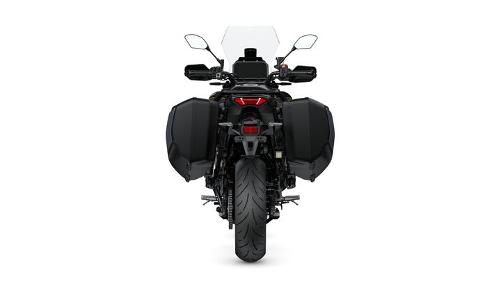 A rear view of a motorcycle equipped with two side panniers, featuring a prominent rear tire and a tall windshield. The bike's tail light and license plate are visible.