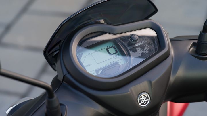 Close-up of a motorcycle dashboard displaying speedometer and fuel gauge, with a digital screen showing 0 km/h and eco mode indicator.