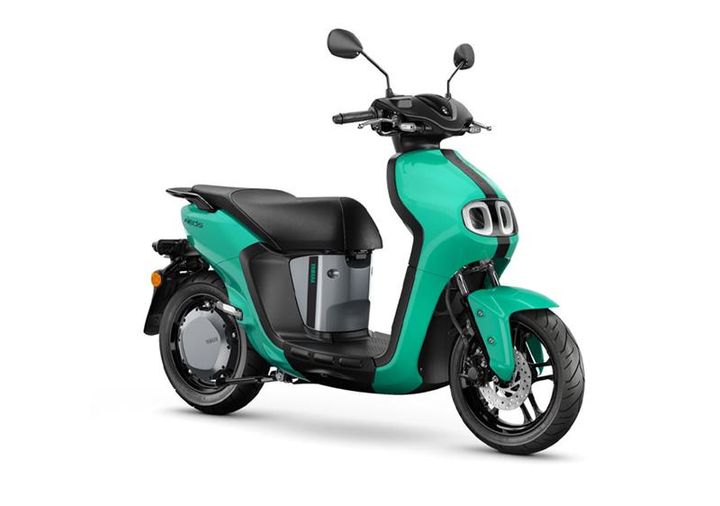 Yamaha 2023 Neos A turquoise electric scooter with a modern design, featuring a black seat and dual headlights, positioned at an angle to showcase its sleek body and front wheel.
