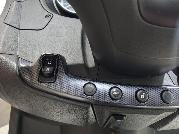 Close-up of a vehicle's gear shift area, featuring buttons labeled "D" (Drive) and "R" (Reverse), along with additional controls including "ASR" and a lock symbol, all set against a textured surface.