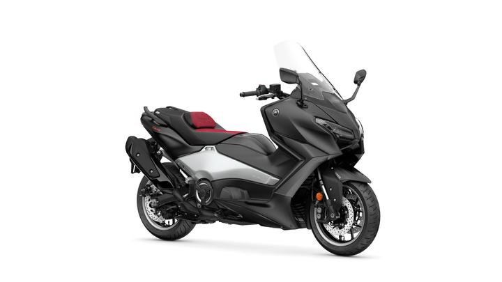 Yamaha 2026 TMAX 25th Anniversary A sleek black and silver touring motorcycle with a sporty design, featuring a comfortable red and black seat and a tall windshield.
