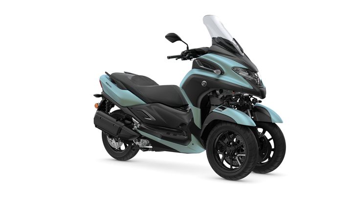 A modern blue and black three-wheeled scooter parked at an angle, showcasing its sleek design, front windshield, and dual front wheels.