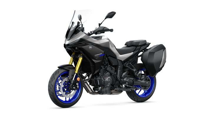 A side view of a Yamaha Tracer 9 GT motorcycle, featuring a sleek black and gray design, gold forks, blue wheels, and side panniers, set against a white background.