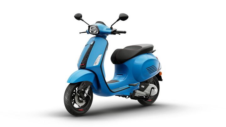 A bright blue scooter with a sleek design, featuring a black seat, front headlight, and a chrome exhaust.