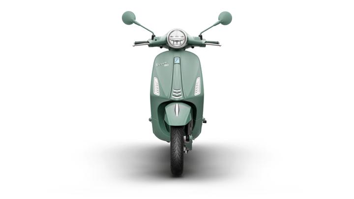 A front view of a mint green scooter with a sleek design, featuring handlebars, a round headlight, and a single tire visible.