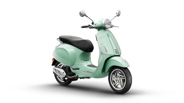 A vintage-style mint green scooter with a black seat, chrome mirrors, and a rounded headlight, positioned at a slight angle against a white background.