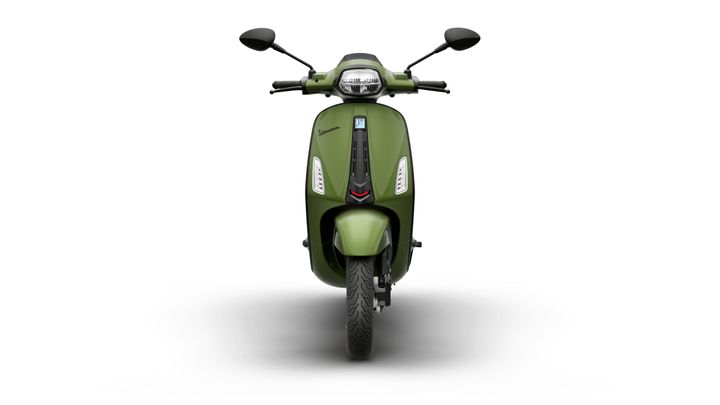 Front view of a green scooter with a sleek design, featuring a modern headlight, handlebars, and a prominent brand logo. The background is plain white, highlighting the scooter's features.