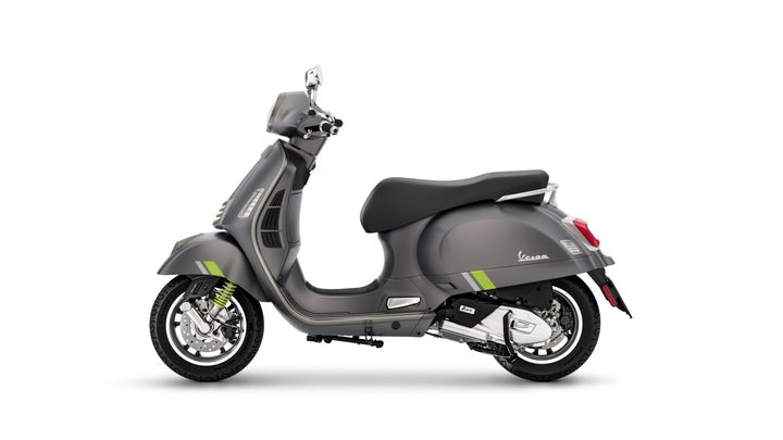 A gray Vespa scooter with green accents, viewed from the side, showcasing its classic design and modern features.