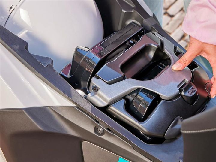 A close-up view of a person's hand interacting with a mechanical component inside a vehicle, showcasing a metallic part and a white spherical object partially visible in the background.