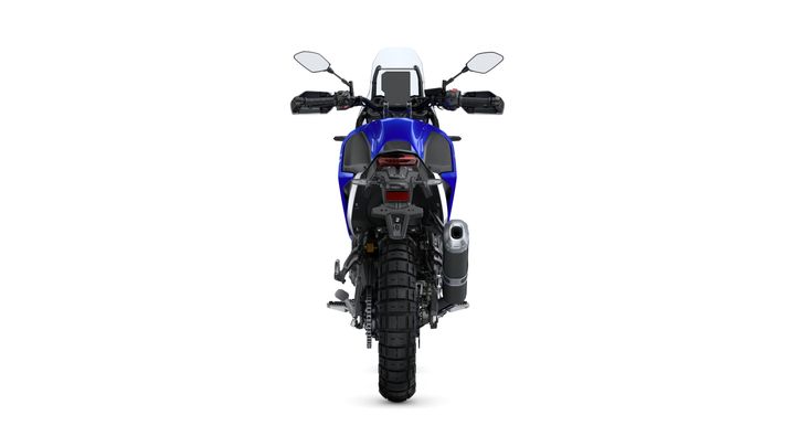 A rear view of a blue motorcycle, showcasing its large rear tire, exhaust, and dual rearview mirrors. The bike features a sleek design with modern styling elements.