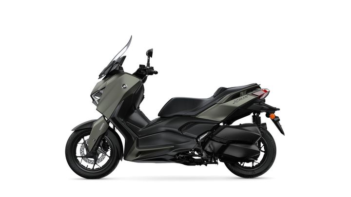 A side view of a sleek, modern Yamaha XMAX scooter in a two-tone matte green and black finish, showcasing its aerodynamic design and sporty features.