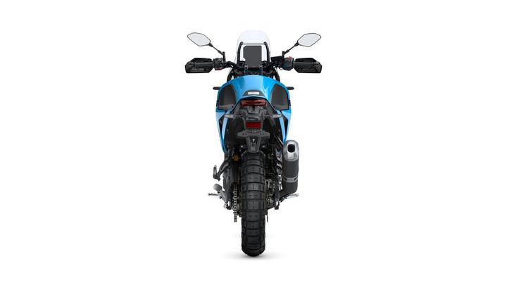 A blue adventure motorcycle viewed from the rear, showcasing its tire, exhaust, and tail lights against a white background.