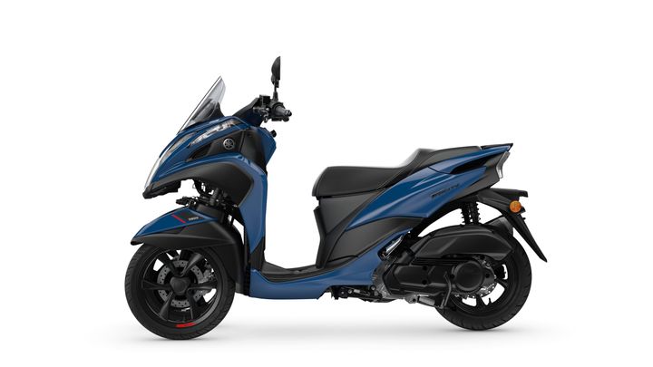 A blue Yamaha Tricity scooter is shown in profile, featuring a modern design with a sleek body, windscreen, and sporty wheels.