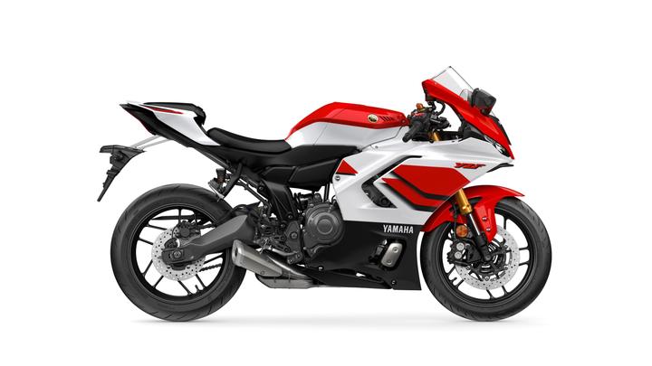 A red and white Yamaha motorcycle, model YZF, is displayed from a side angle, showcasing its sleek design, sporty stance, and advanced features.