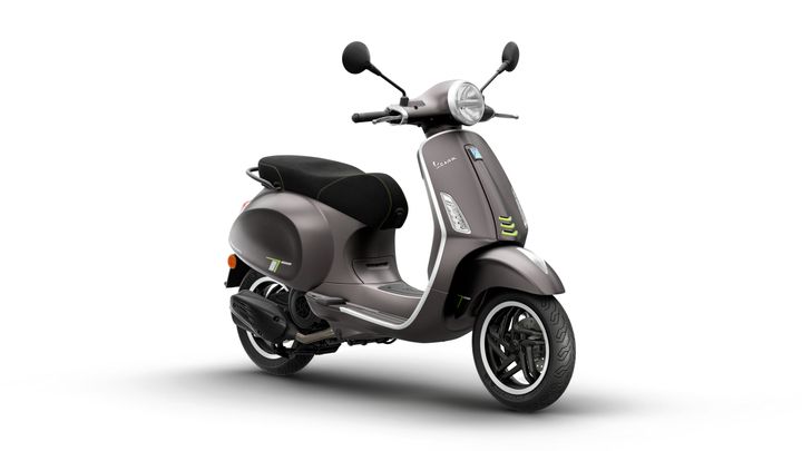 A stylish gray scooter with a black seat and green accents is displayed at an angle, showcasing its iconic design and chrome details.