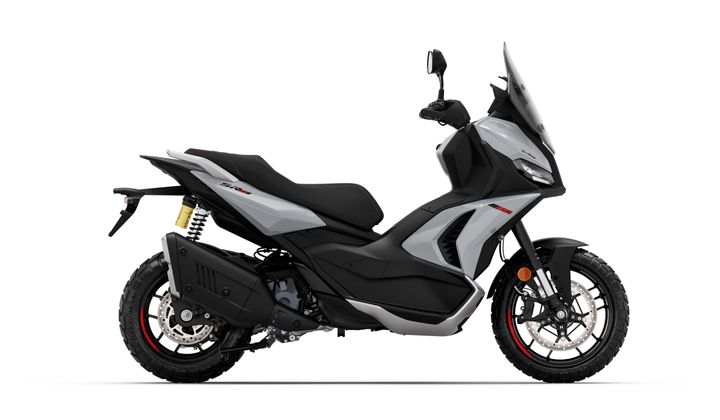Side view of a modern gray and black scooter with a sleek design, featuring off-road tires, dual suspension, and a protective windshield.