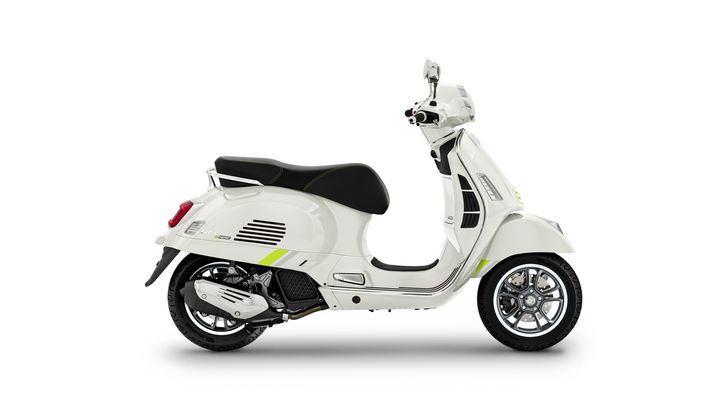 A sleek white scooter with a black seat and yellow accents, viewed from the side, showcasing its modern design and stylish wheels.