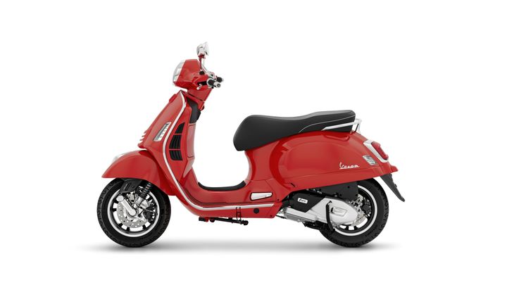 A sleek red Vespa scooter with a glossy finish, featuring a black seat and modern chrome accents, is shown in profile view against a clean white background.