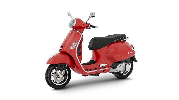 A bright red scooter with a vintage design, featuring a rounded headlamp, a black seat, and chrome accents, positioned at a slight angle on a white background.