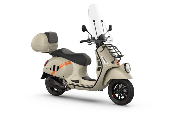 A beige scooter with a sleek design, featuring a windshield and a rear storage box, showcasing orange stripes and a black seat, positioned on a white background.