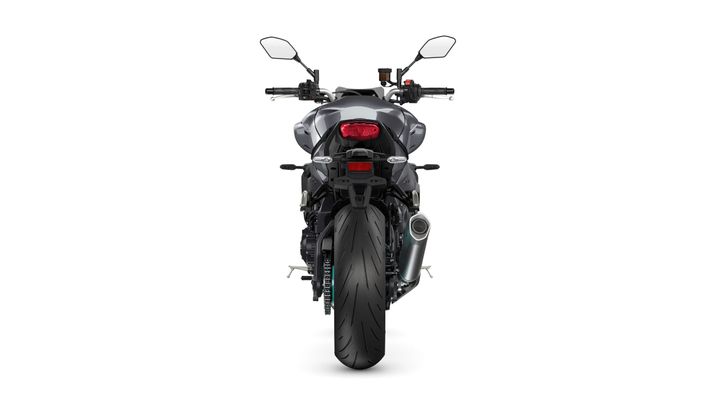 A rear view of a modern motorcycle with a sleek, black body, prominent rear tire, and dual rearview mirrors. The taillight is illuminated, and there is an exhaust pipe on the right side.