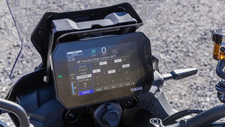Close-up of a motorcycle's digital display showing the Yamaha Ride Control settings, including modes like Sport, Street, and Rain, along with various performance metrics such as gear, speed, and trip information. The screen features icons for power and traction control.