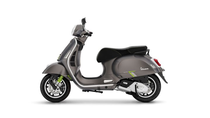 A sleek gray Vespa scooter with green accents, seen from the side, showcasing its modern design and stylish curves.