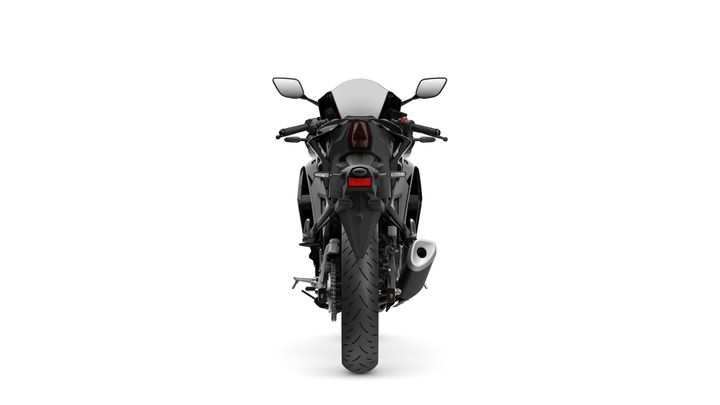 A rear view of a modern motorcycle against a white background, showcasing its sleek design, prominent rear tire, exhaust pipe, and minimalistic tail lights.