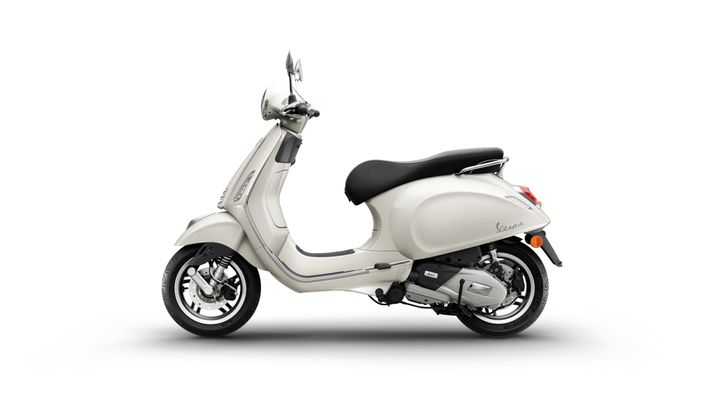 A light-colored scooter in profile view, featuring a comfortable black seat, chrome details, and modern design elements. The scooter is positioned on a minimalist background.