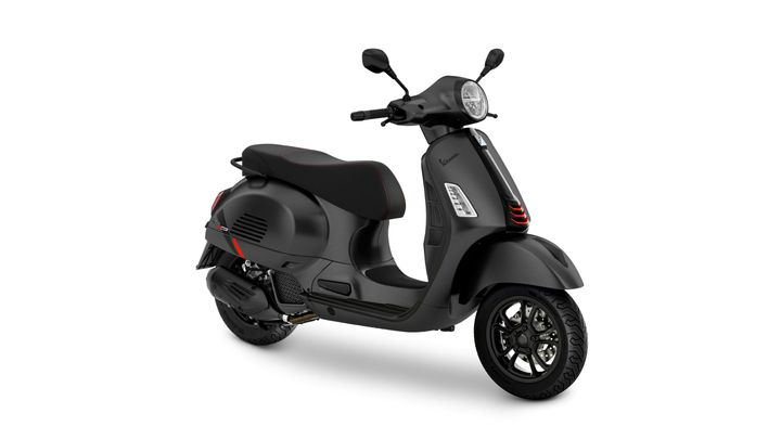 A black scooter with a modern design, featuring a sleek body, circular headlight, and sporty wheels, set against a white background.
