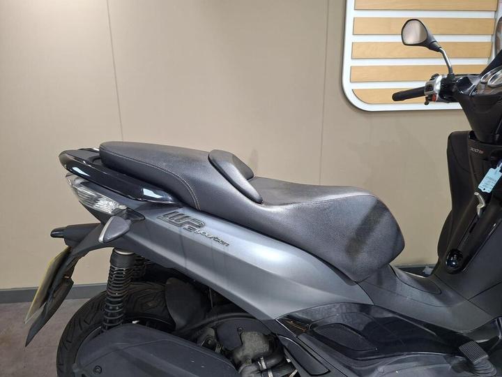Close-up of a black scooter seat with sleek design, displayed against a neutral background.
