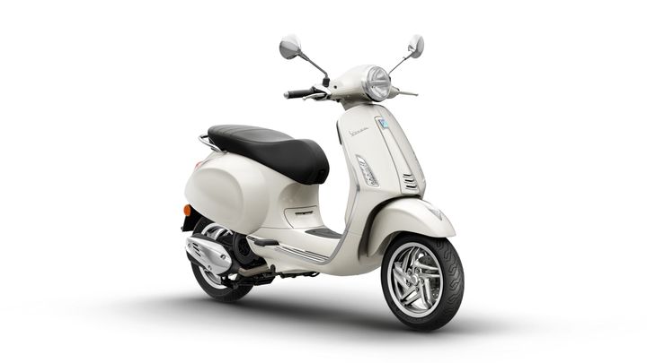 A vintage-style cream scooter with a black seat, chrome accents, and a front headlight, positioned at an angle on a white background.
