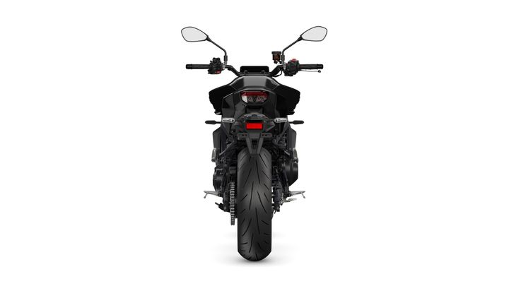 A rear view of a black motorcycle showcasing its sleek design, large rear tire, and instrumentation on the handlebars against a white background.