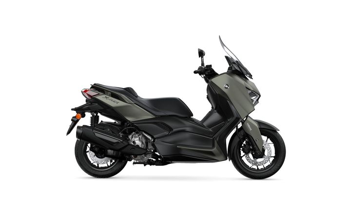 A sleek, modern scooter in a matte olive green finish, featuring a streamlined design, windscreen, and prominent front and rear lights, positioned against a white background.