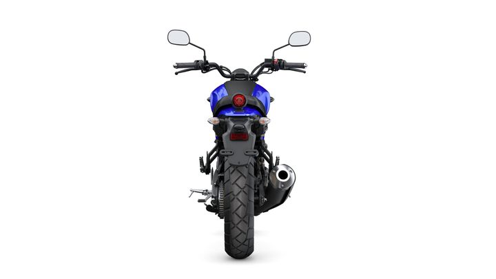 A rear view of a blue motorcycle, showcasing its tail light, mirrors, and exhaust pipe against a white background.