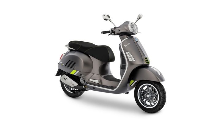 A sleek, modern scooter in metallic gray with green accents, featuring a comfortable black seat, stylish handlebars, and distinct round headlight.