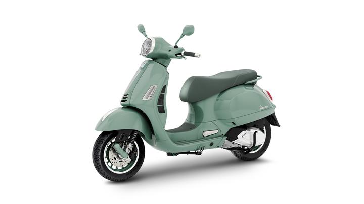 A mint green scooter with a classic design, featuring a round headlight, a single seat, and chrome accents, positioned at an angle to showcase its profile against a white background.