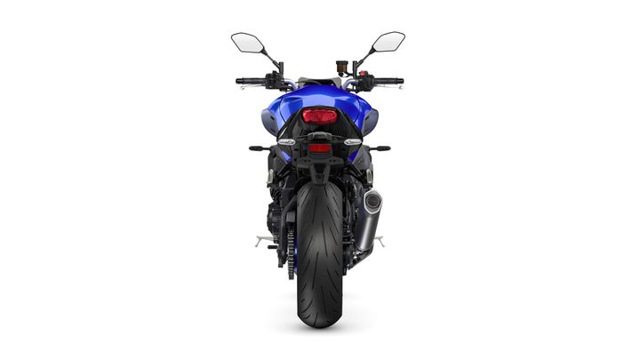 A blue motorcycle viewed from the rear, showcasing its sleek design, large rear tire, dual exhaust, and prominent taillight.