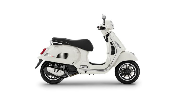 A side view of a white scooter featuring a black seat and sleek design elements, highlighting its chrome accents and sporty tires.