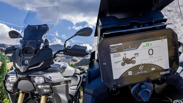 A close-up view of a Yamaha motorbike featuring a prominent windshield and an advanced digital display showing ride information such as gear, speed, and time. The background includes a scenic landscape with mountains and clear skies.