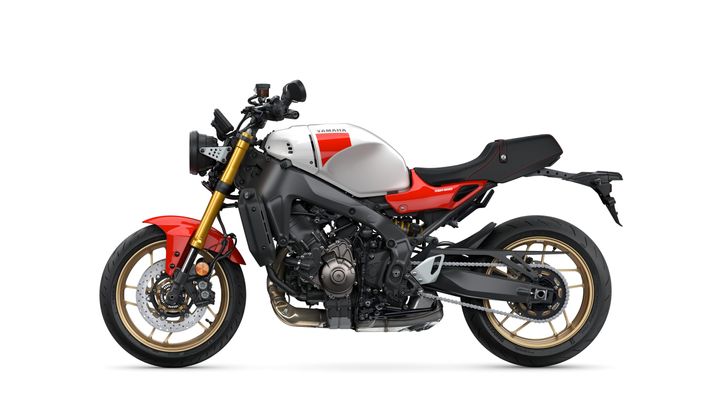 A Yamaha motorcycle with a sleek design featuring a red front fender, silver fuel tank with red accents, and black frame components. The bike has gold alloy wheels and a sporty stance, set against a white background.